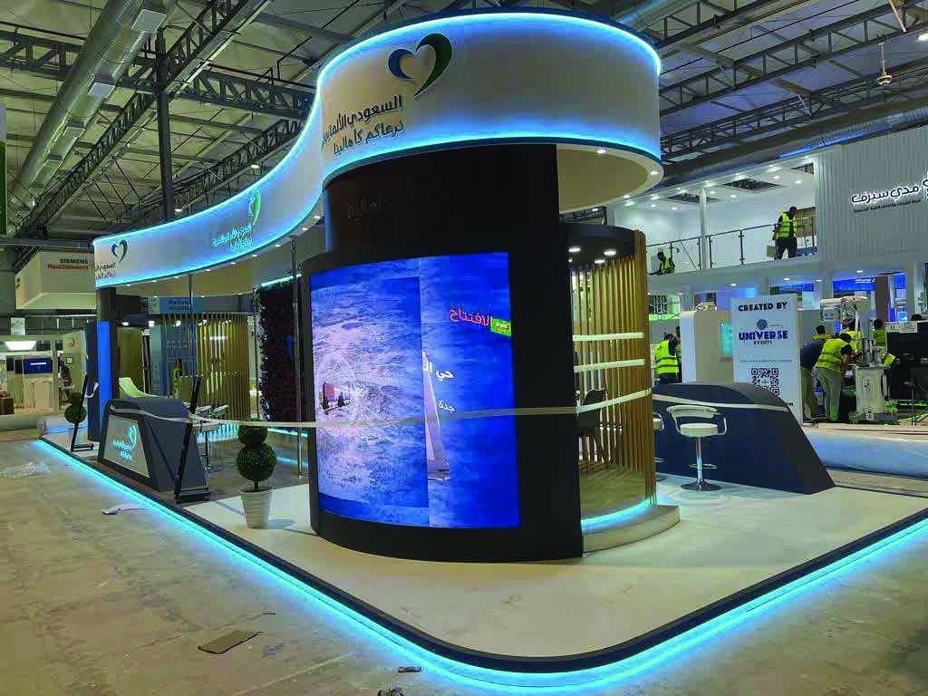 An exhibition stand with a curved façade, a full-height LED screen and a lit perimeter on the show floor